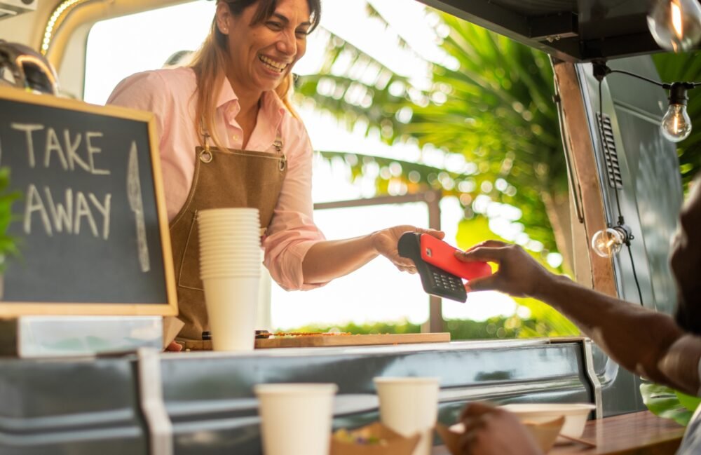 Cheerful black woman paying for coffee in cafe