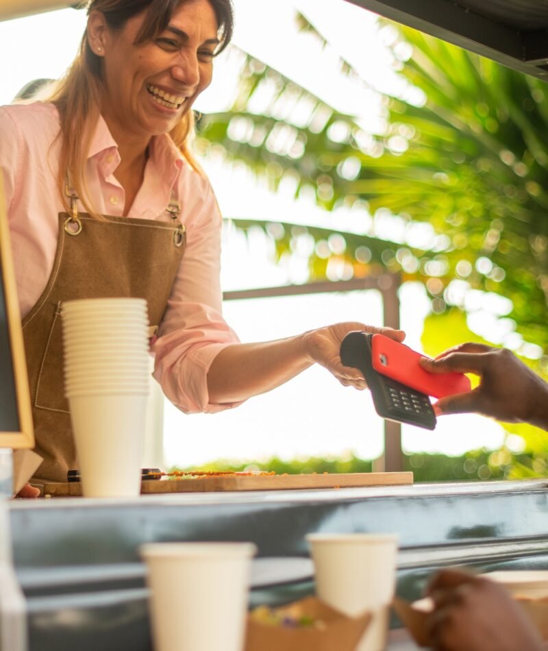 Cheerful black woman paying for coffee in cafe