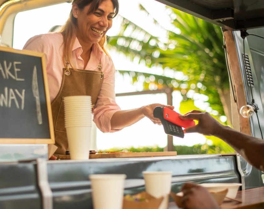 Cheerful black woman paying for coffee in cafe
