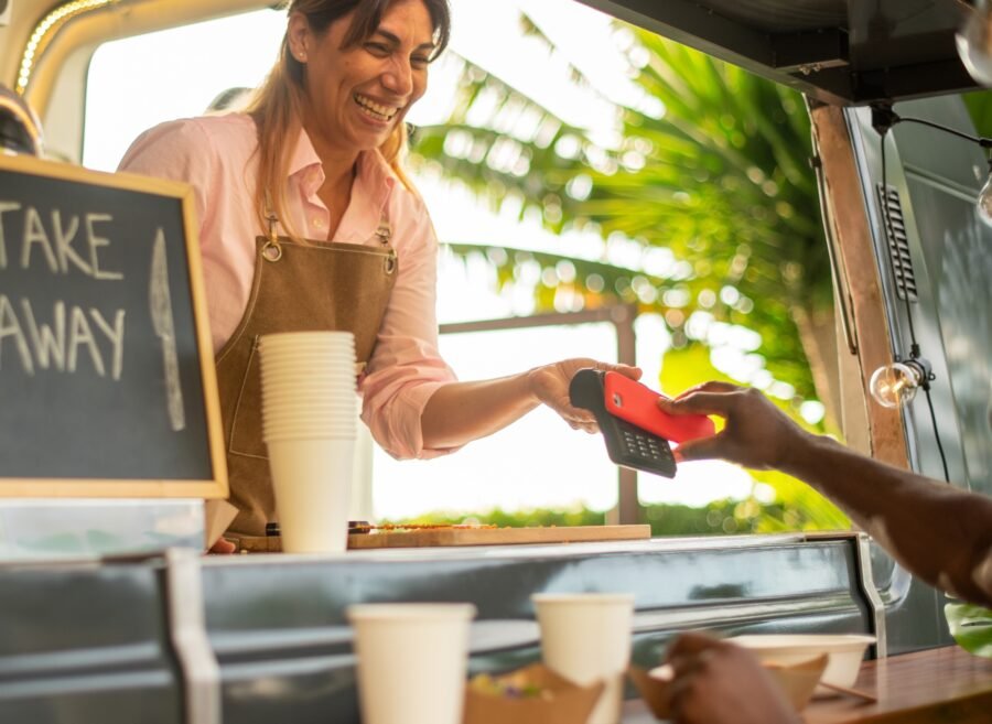 Cheerful black woman paying for coffee in cafe
