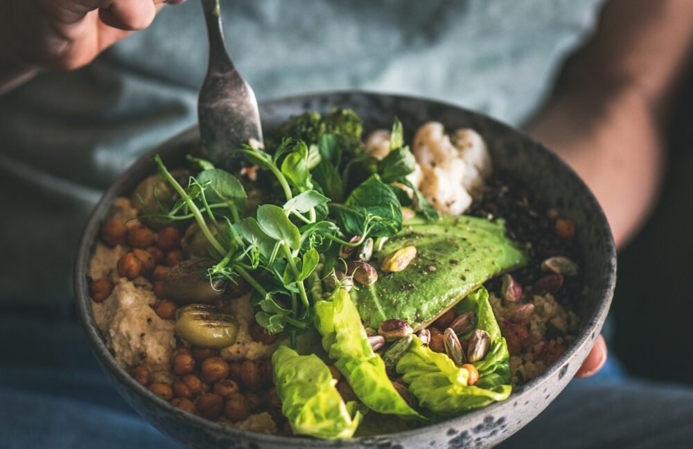 Woman eating healthy vegan dish from bowl, square crop
