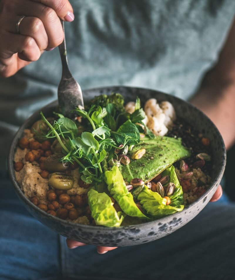 Woman eating healthy vegan dish from bowl, square crop
